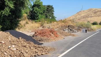 Piles of illegally dumped construction debris line the side of the road