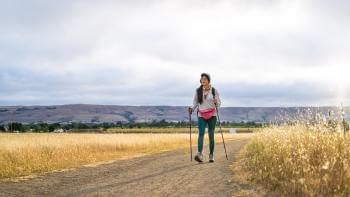 hiker with walking sticks on dirt trail