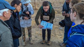 group of hikers surrounding and looking at a book