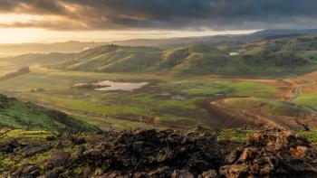 sunrise over green hills and a small lake