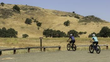 Two bikers head towards a trail at Coyote Valley OSP