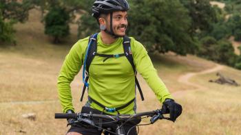 A person sits on their bike looking off to the side of the camera while enjoying the scenes of nature