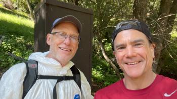 Loren Lewis outdoors with another individual with a hat and backpack