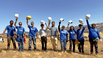 Student Conservation Association students lift their hard hats over their heads while posing for a photo at MOCR