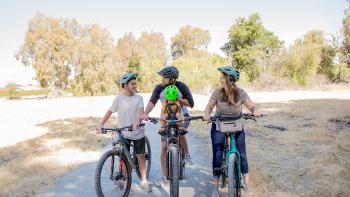 A family of four bikes on a nature trail