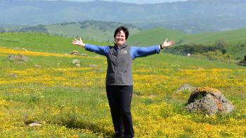 Andrea Mackenzie in a field of green grass and wildflowers