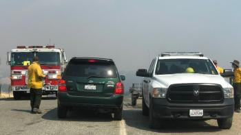 Open Space Technicians work with CalFire units during a fire, three vehicles in a row