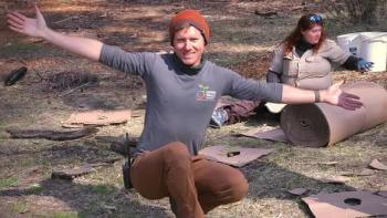 Man squattimg on the dirt floor, smiling, with his arms wide open