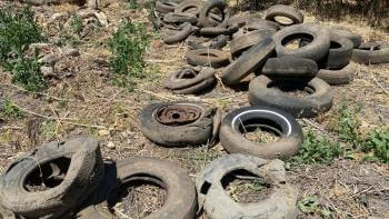 an assortment of old, battered tires on the dirt floor