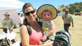 Woman smiling and holding a young child with a hat