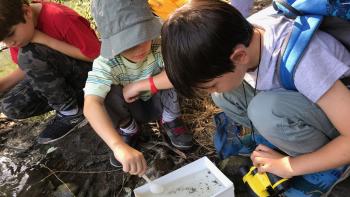 children playing with a box of water in the dirt