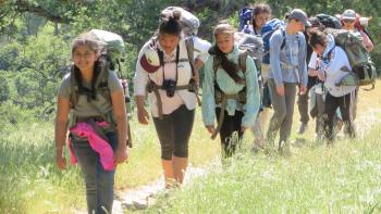 Group of women hiking a trail with backpacks on