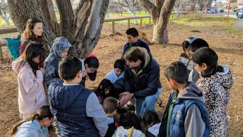 Group of children in a circle around the speaker of the group