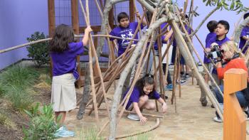 Children playing with tall stick huts 