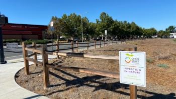 Open Space Authority sign that says "investing in nature" on a wooden fence outdoors