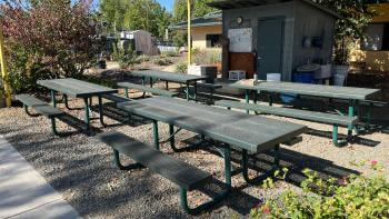 4 green tables and benches near a school building