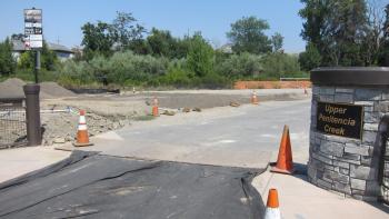 A trail with cones at the entrance next to a stone monument that says "Upper Penitencia Creek"