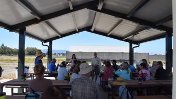 Group of adults sitting under gazebo listening to a man and woman present