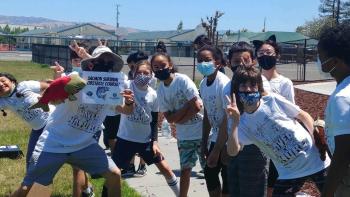 Large group of kids wearing white "saved by nature" tee shirts