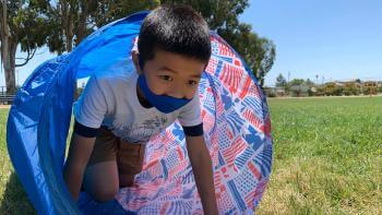 young boy crawling through play tunnel