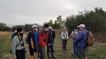 Group of people gathered around listening to a man talk