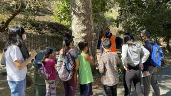 Group of children listening to a speaker outdoors
