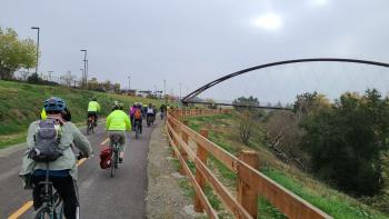A group of cyclists riding down a road with a cloudy sky 