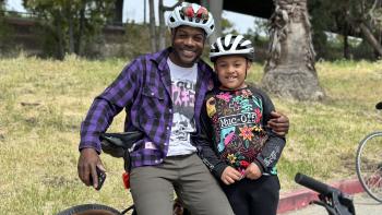 A father and son smiling on a bicycle