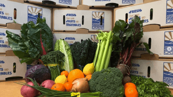 Fruits and vegetables propped up in front of a stack of cardboard boxes