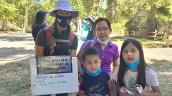 A family smiling and holding up a sign that says "what was your favorite part of the bioblitz?"
