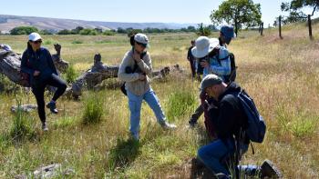 Group of people in a field of grass with cameras and binoculars