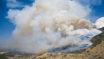 Smoke from a wildfire looms over golden hills