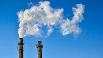 CO2 emissions exit from two smoke stacks against a blue sky background.