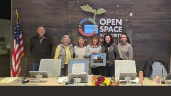 Group of 6 Open Space Authority board directors standing against a dark gray wood wall