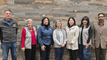 Seven members of the Open Space Authority's Board of Directors pose for a photo against a wood backdrop.