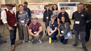 A group of people gather around a scientific poster.