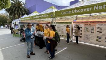 Open Space Authority staff talk to a visitor at a Coyote Valley Discovery Days event booth.