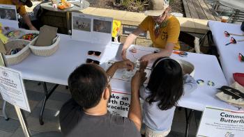 A father and daughter create an Earth Day bracelet with the help of an Open Space Authority staff member.