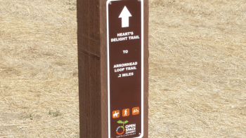 A trail sign reads "Heart's Delight Trail to Arrowhead Loop Trail"
