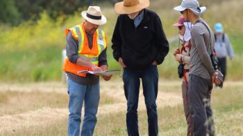 A group of three people stand with a volunteer learning about the Laguna Seca wetland.
