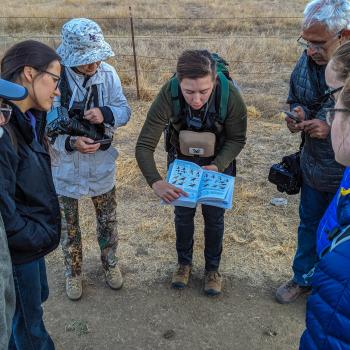 group of hikers surrounding and looking at a book