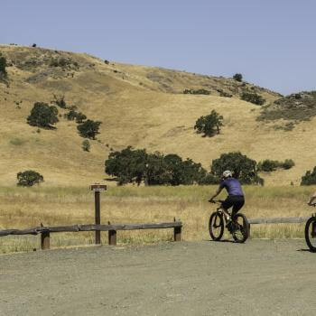 Two bikers head towards a trail at Coyote Valley OSP