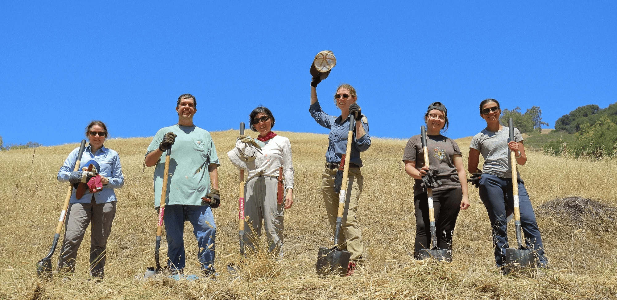 Volunteers pose for a photo on a golden hill at Furtado Barn