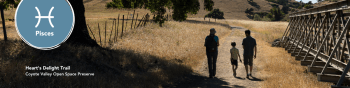 Heart's Delight Trail with a family of three walking on a trail surrounded by yellow grass. Pisces symbol in the left corner.