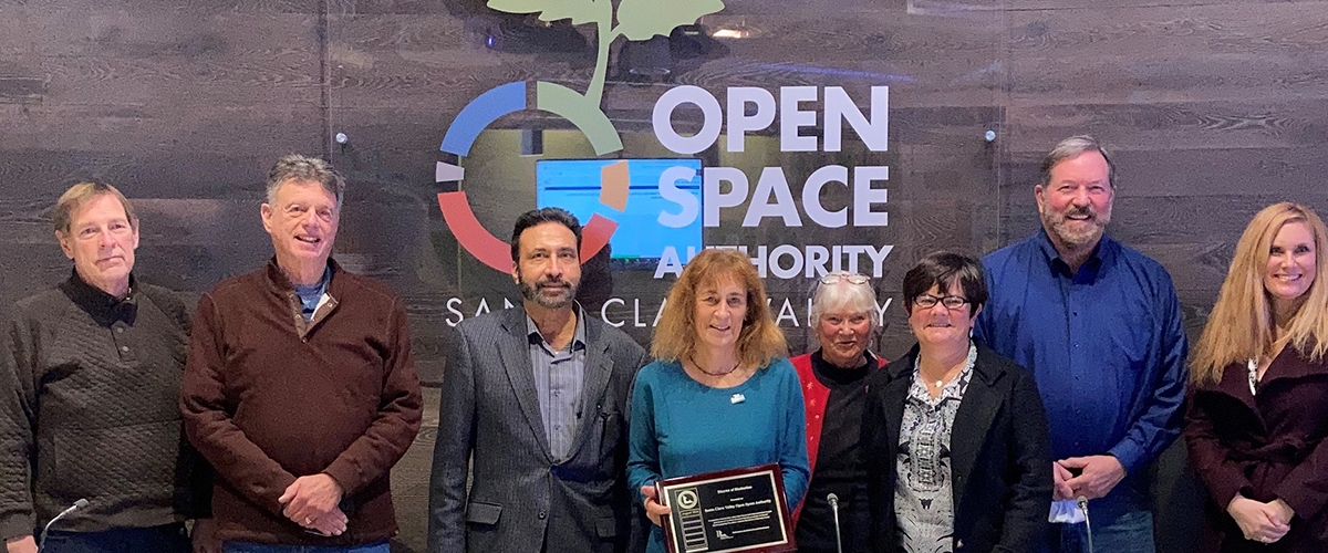 Three Open Space Authority staff members smiling at camera and holding award