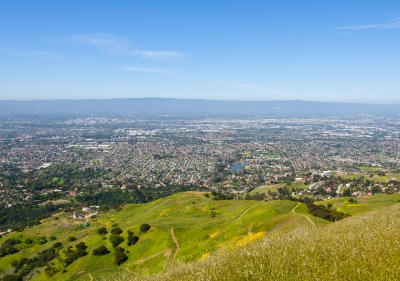 Looking down from green Sierra Vista hillsides across urban San Jose to the Santa Cruz Mountains in the hazy distance