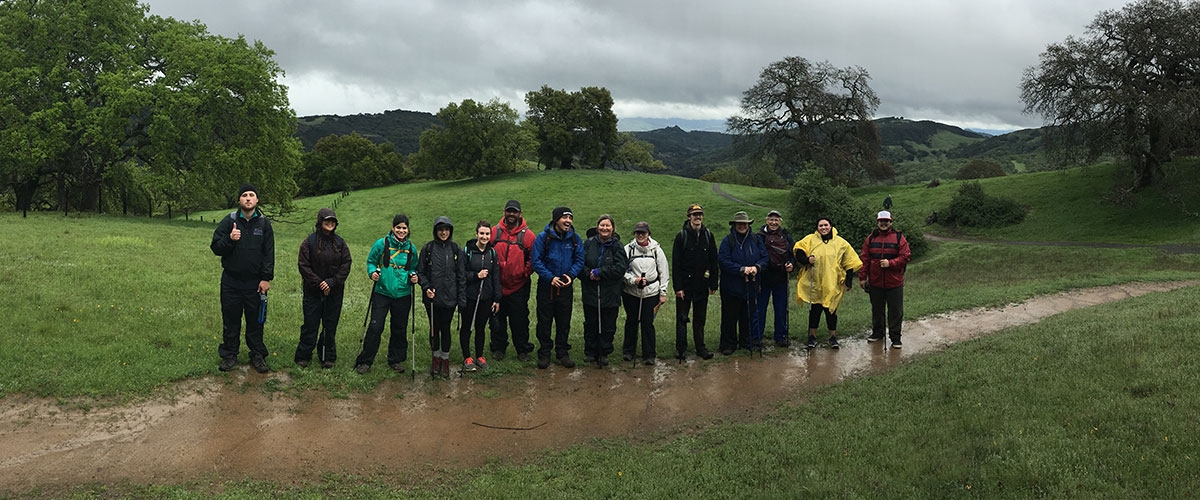 Young adult hikers in rain gear smiling on trail