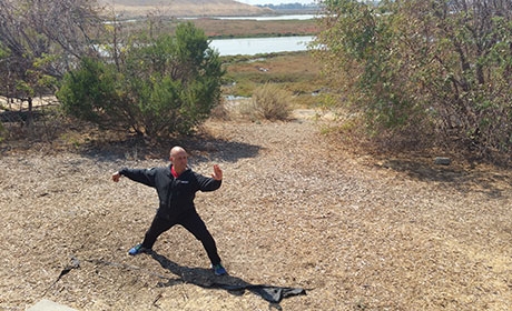 Man in tai chi pose at the Don Edwards San Francisco Bay National Wildlife Refuge on bank above the water