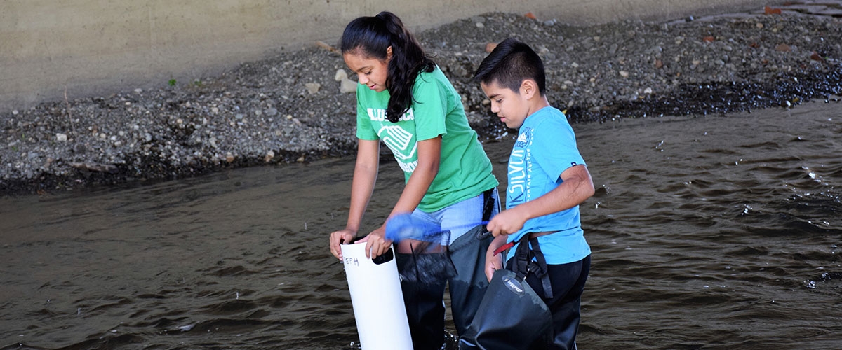 Two students using waders to explore creek
