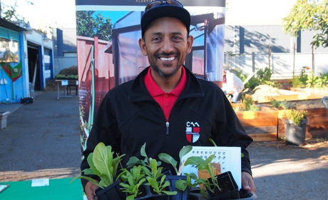 Valley Verde representative holding tray of plants in containers with garden in background